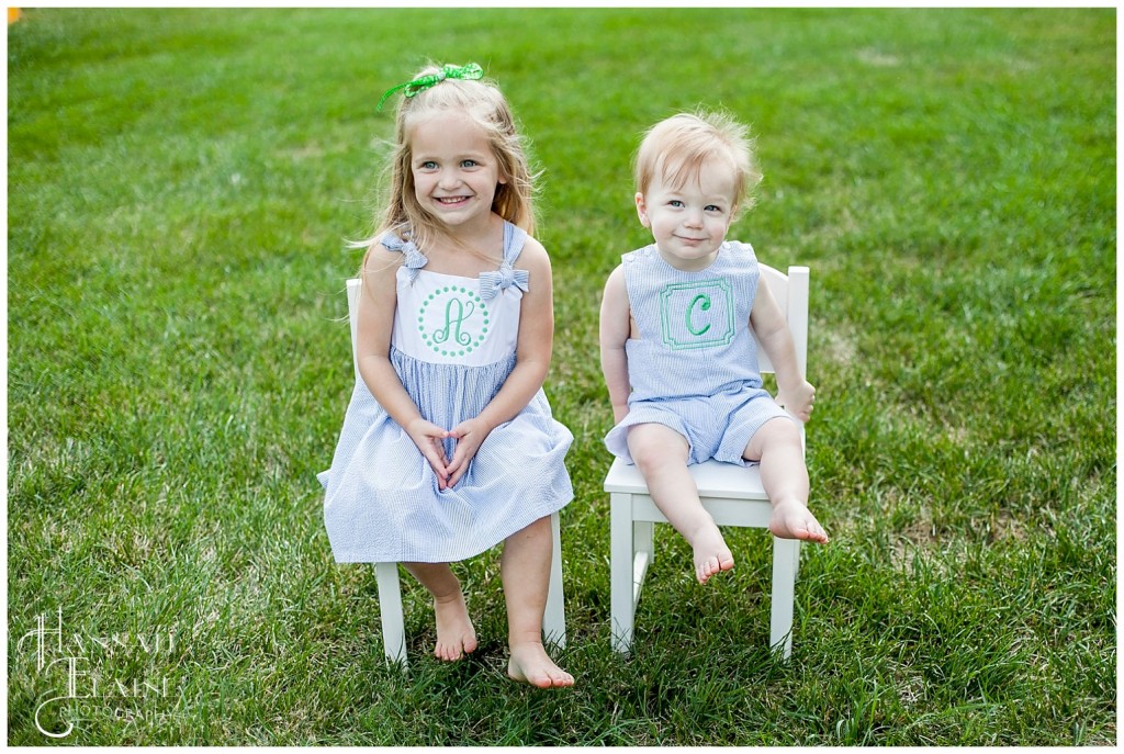 blond siblings hanging out on white chairs in the back yard