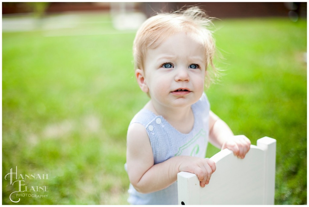 little blue eyed boy sits backwards in his white chair