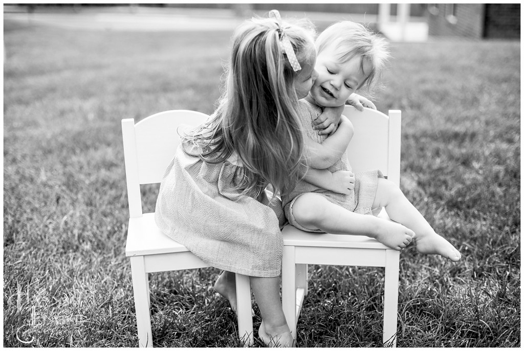 black and white photo of sister kisses her little brother