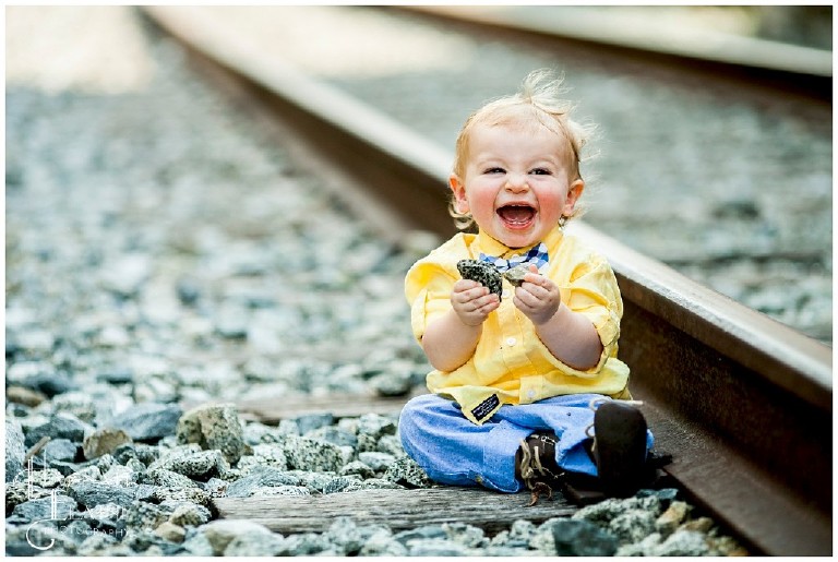 boy plays with the rocks on train tracks
