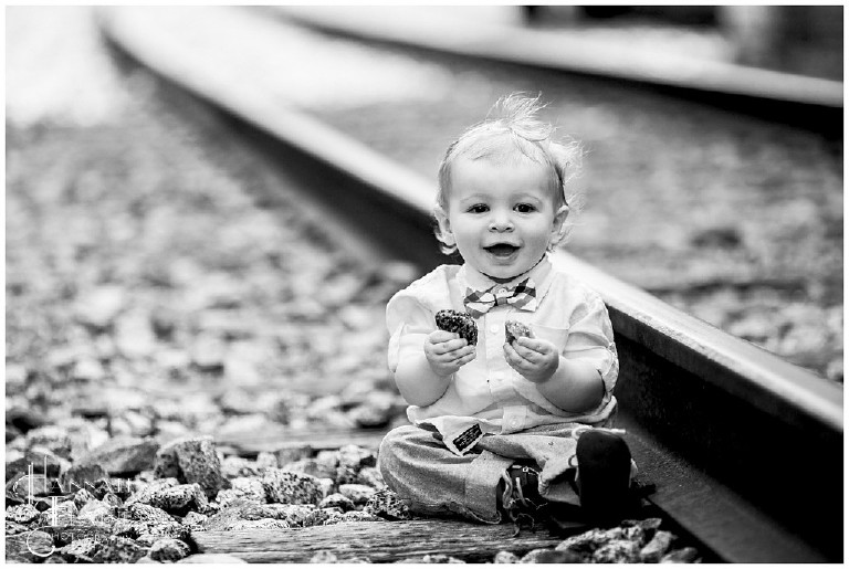 black and white boy plays with rocks along the tracks