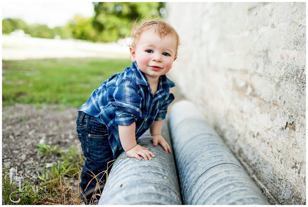 boy crawling around on some giant metal pipes