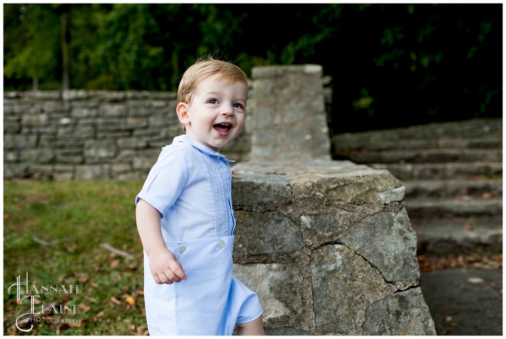 boy in blue jumper climbs on the rock wall