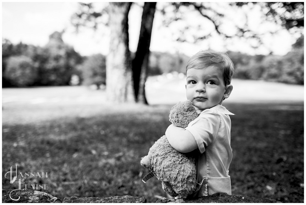 black and white image of little boy hugging his teddy bear