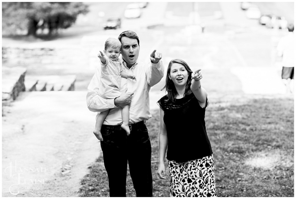 mom and dad mimic their toddler who is pointing to go up the stairs