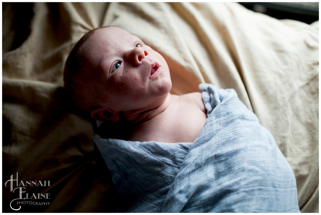 baby in blue cheesecloth looking out window