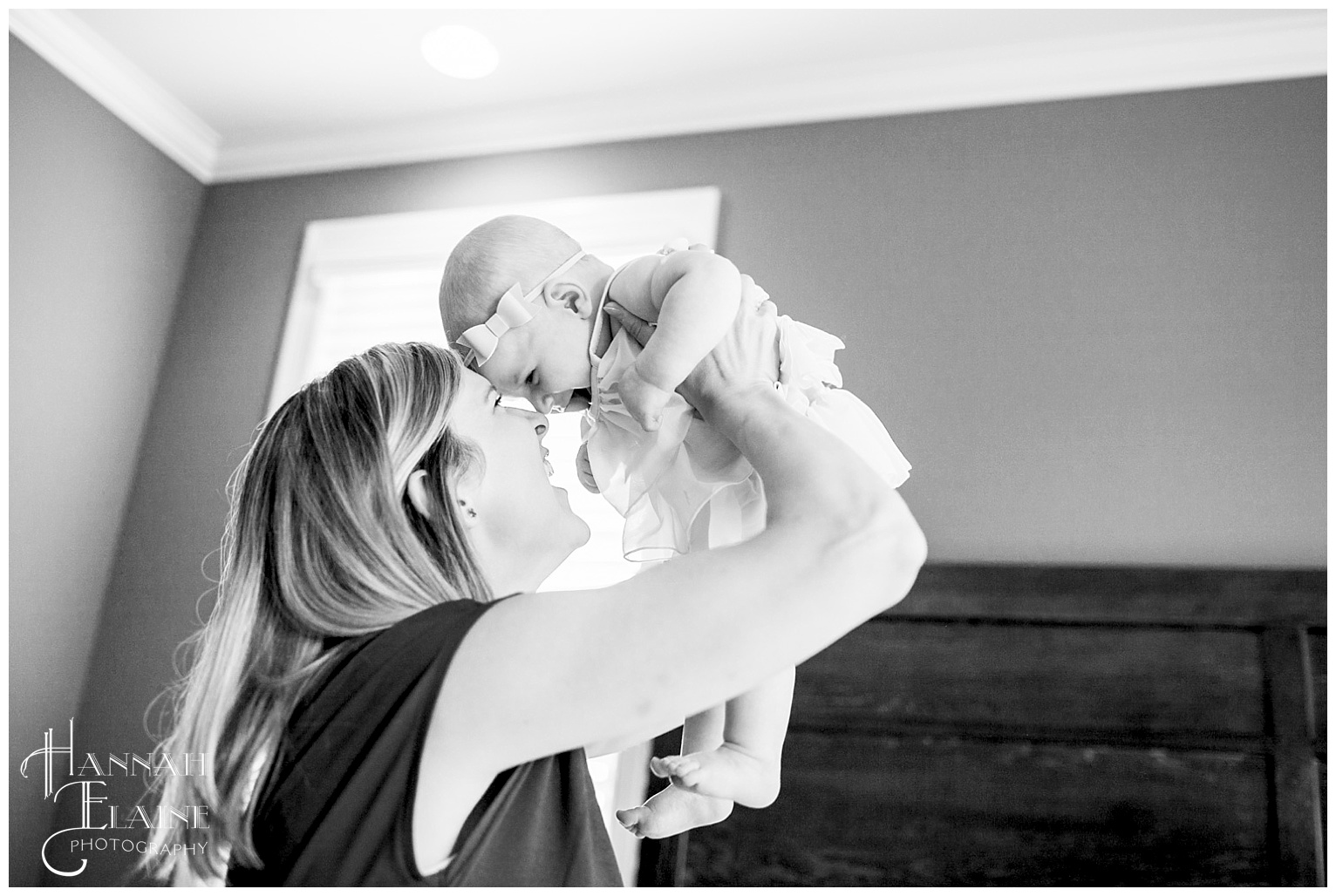 black and white image of mom hoisting baby up high