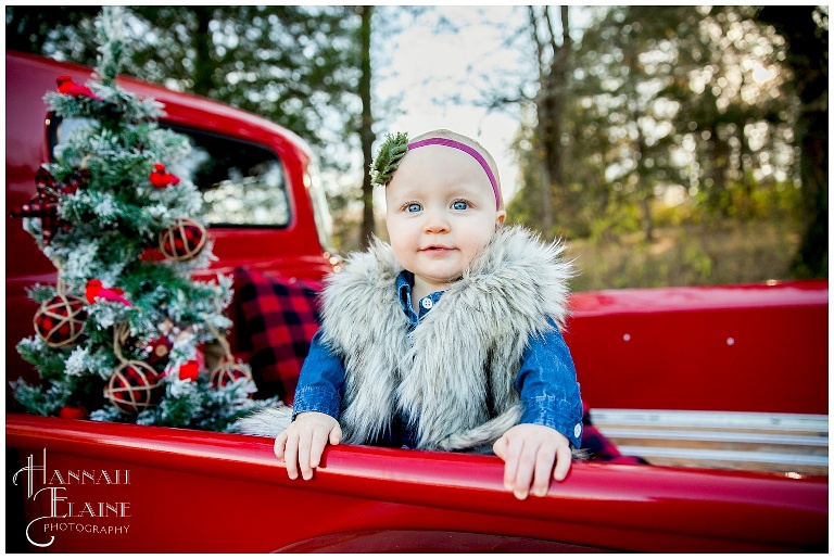 olivia in her fur coat in the christmas themed red pickup truck