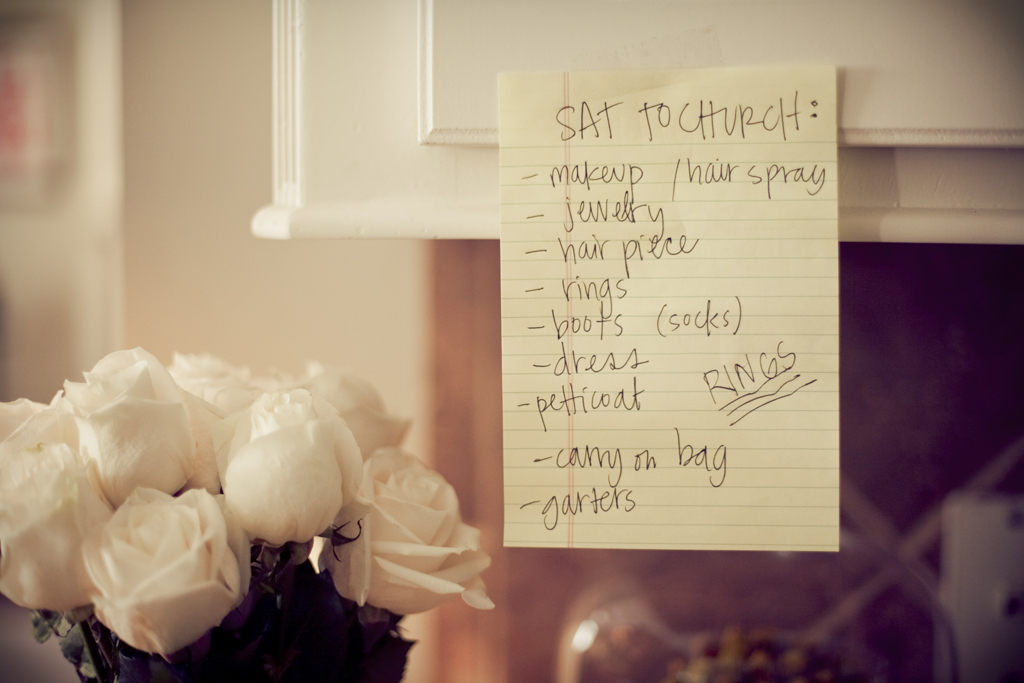 a list of things to remember to take to the church hangs on a cabinet next to white roses