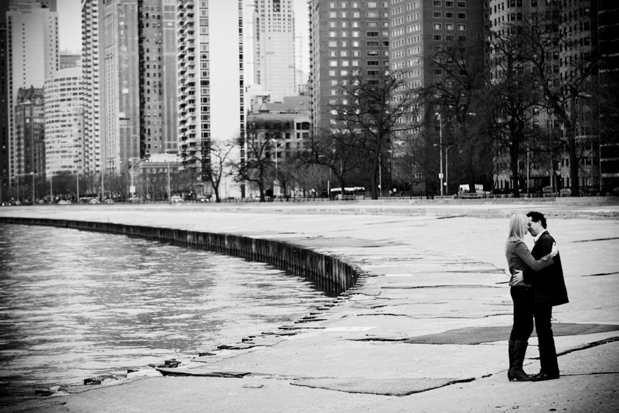 couple poses on the edge of lake michigan with chicago skyline in the background, black and white