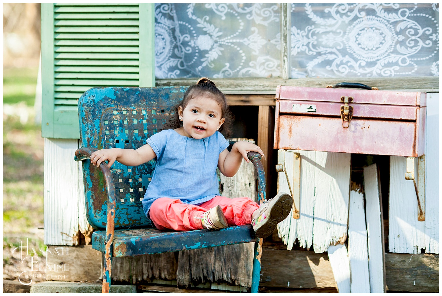 a cute latina girl smiles on a blue rustic lawn chair