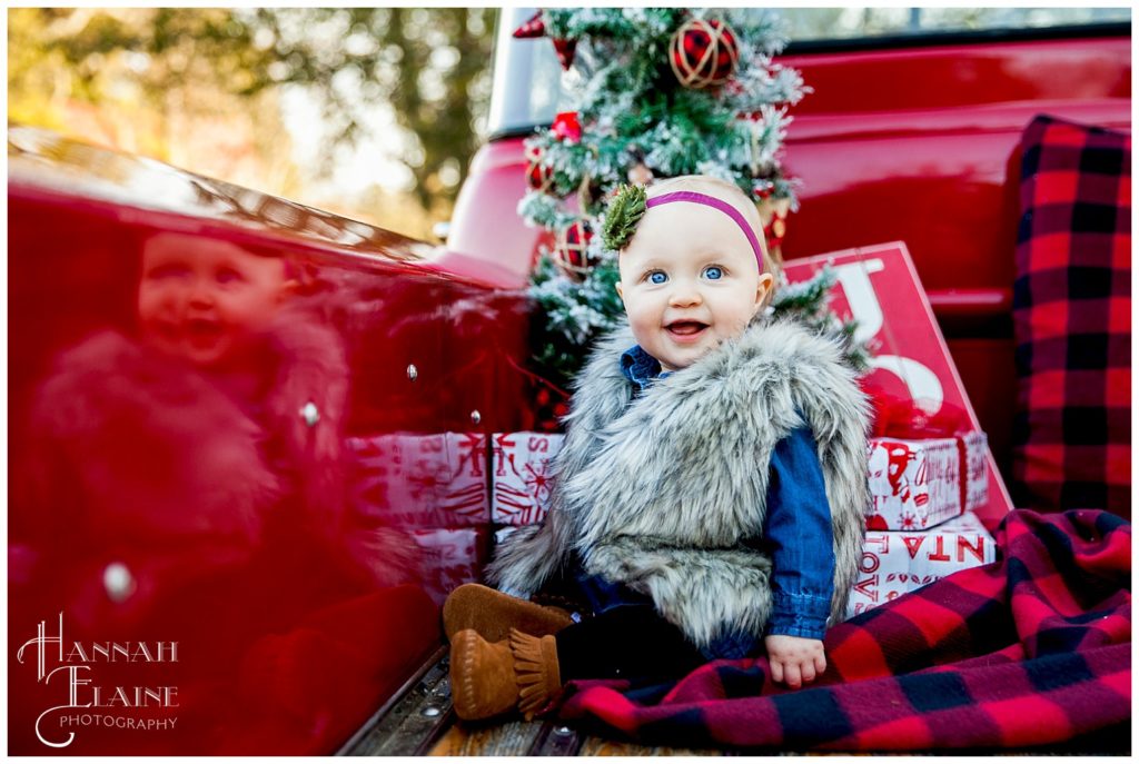 christmas themed shoot with little girl in fur vest in gravel road tradition's vintage red pickup truck